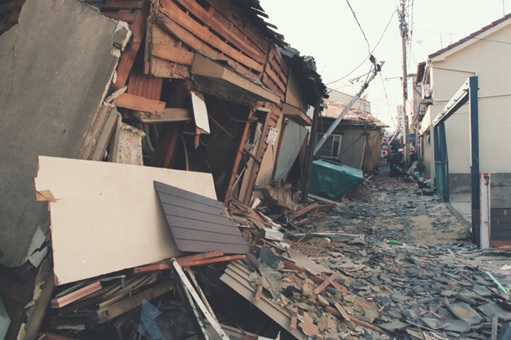 地震で倒壊した家屋で通行できなくなった道路の写真