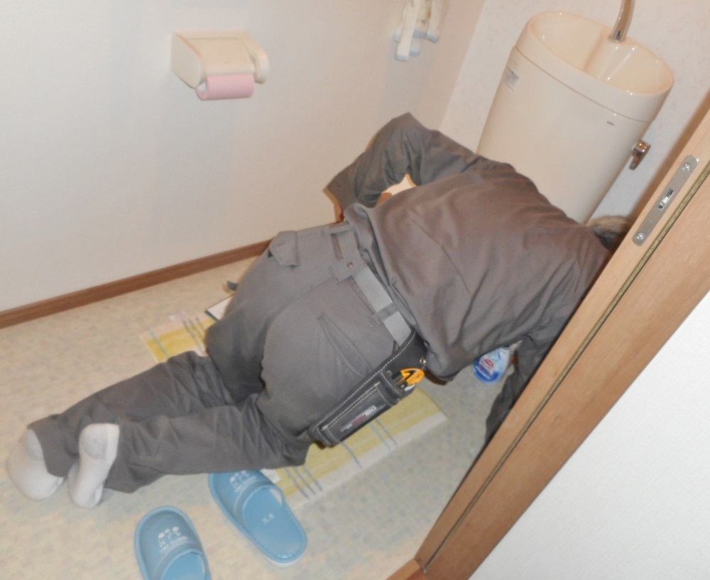トイレの水漏れ点検をする作業員
