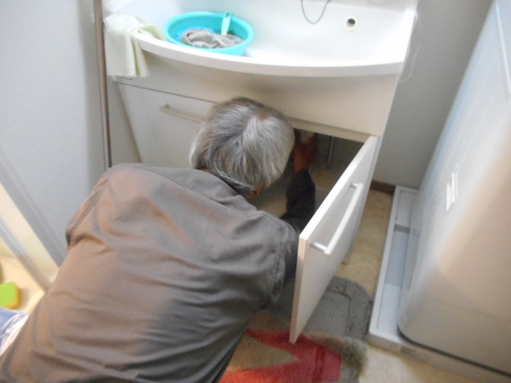 洗面台下の配管を点検する様子