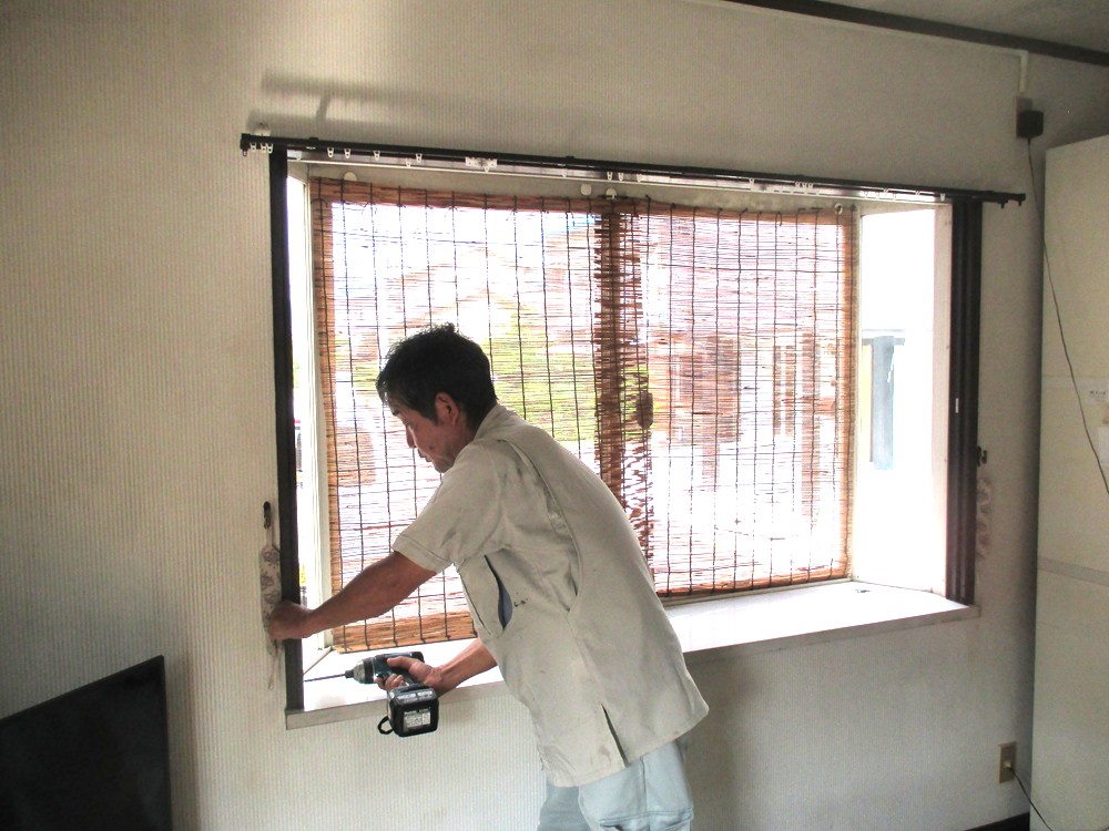 内窓の枠を丁寧に調整している職人の施工風景