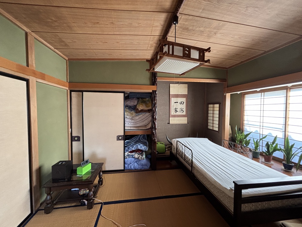 畳の和室を別角度から撮影。収納やベッドがあり、暮らしの様子が分かるリノベーション前の状態。