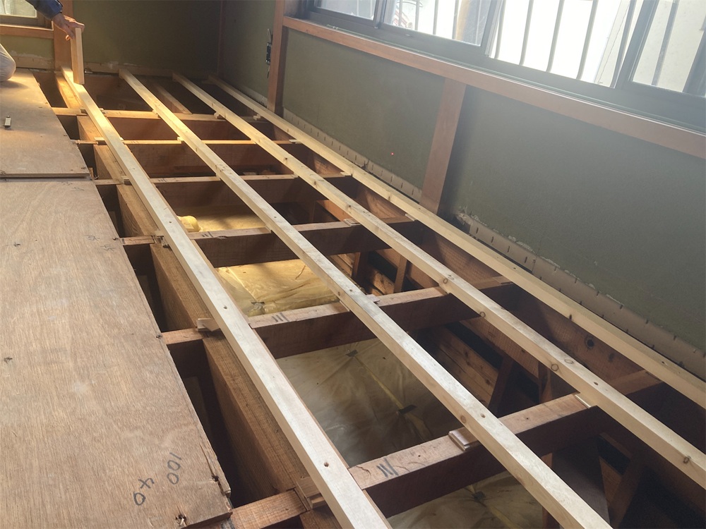 床を解体し、高さを少しずつ調整しながら、まっすぐな床に整えている工事中の様子。