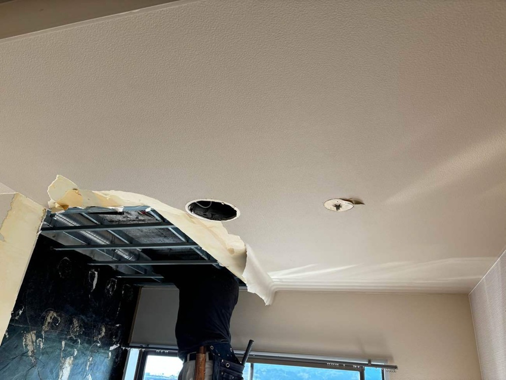 天井からの水漏れ原因を調べるため、マンションの天井を開けて調査している様子