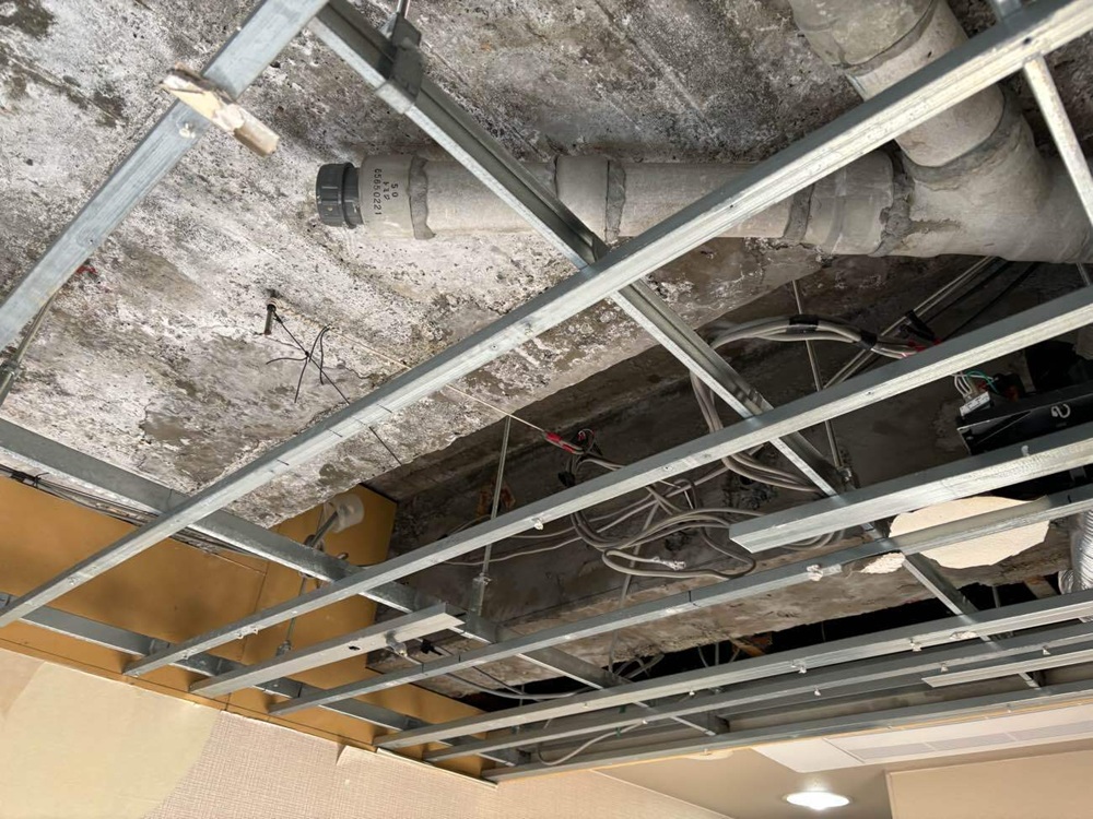 マンションの天井裏で配管を確認し、水漏れの原因を調査している様子