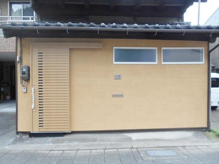 リフォーム後の外観。片引戸の玄関と壁で落ち着いた印象になり、安心感のある玄関まわりに変わった住まい